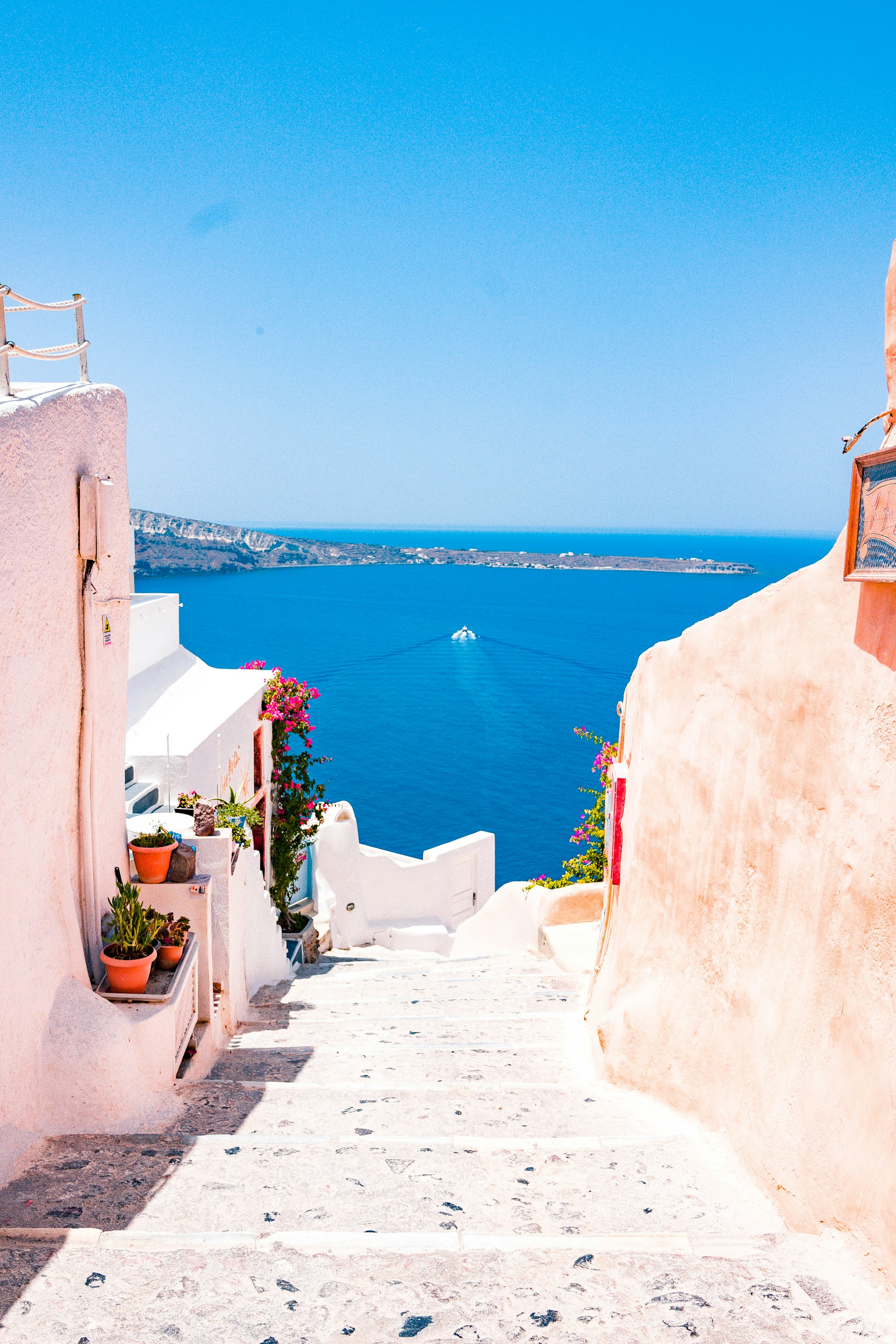 Sunlit whitewashed steps in Santorini opening onto the deep blue Aegean Sea